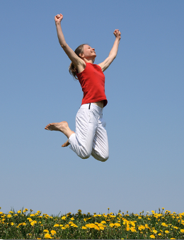 Happy woman leaping in air in field of flowers