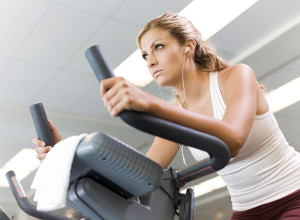 Woman exercising on cycle machine in gym